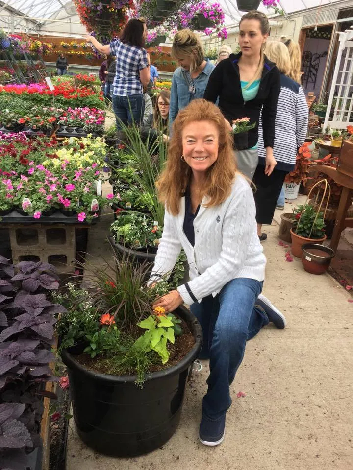 Colleen Whitlow kneeling beside flower planters